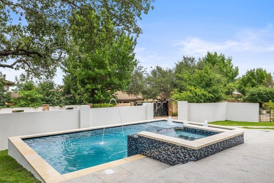 Geometric pool and spa combination featuring a fountain, mosaic tile detailing, and light-toned coping