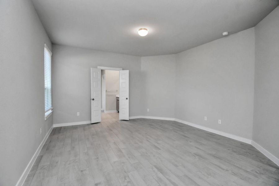 Escape and relax in the exquisite primary suite, a haven to unwind after a long day. The spacious room, boasts soothing paint tones, high ceilings, and expansive windows adorned with privacy blinds.