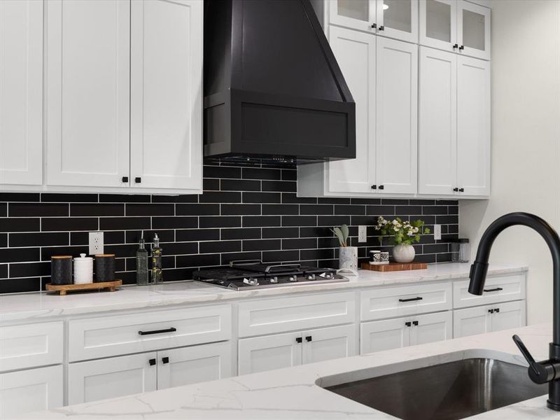 Kitchen featuring white cabinetry, light stone countertops, glass fronted cabinets, and decorative backsplash