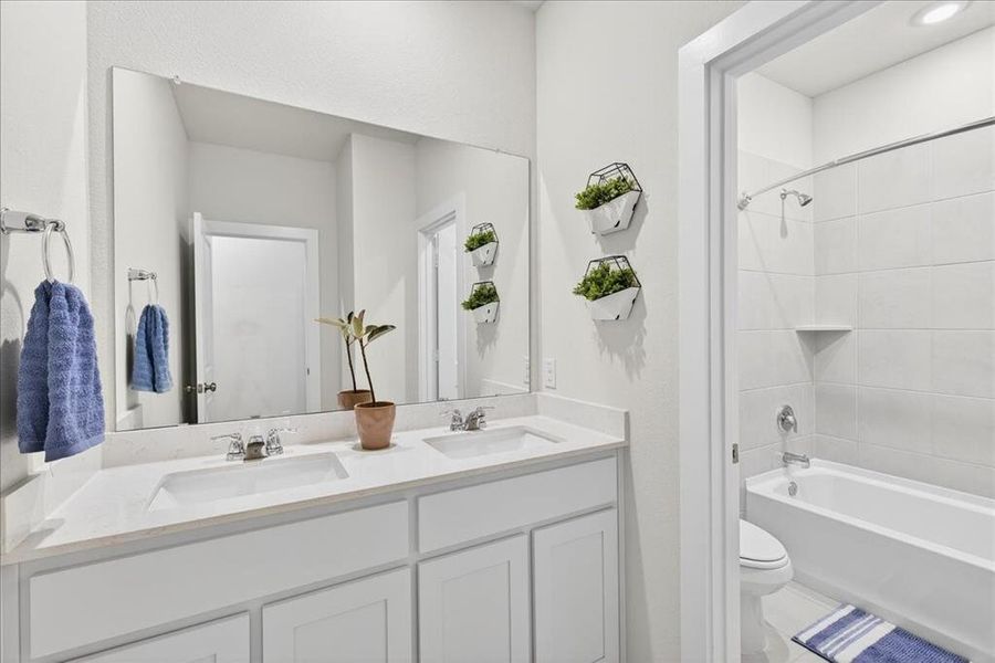 Secondary bathroom located by the secondary bedrooms with double sinks and a door separating the sinks from the tub area