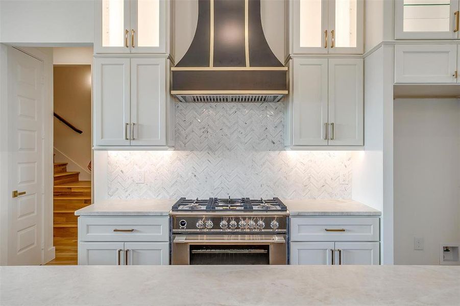 Kitchen featuring white cabinetry, hardwood / wood-style flooring, tasteful backsplash, wall chimney range hood, and stainless steel stove