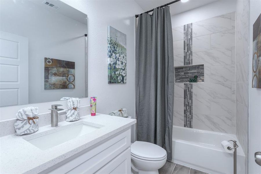 Full bathroom featuring shower / bath combo with shower curtain, vanity, and toilet