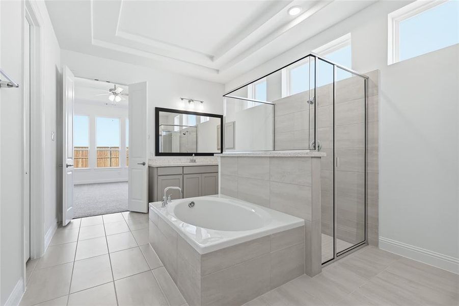 Full bath with a bath, a shower stall, vanity, light tile patterned floors, and a raised ceiling Full bath with a bath, a shower stall, vanity, light tile patterned floors, and a raised ceiling