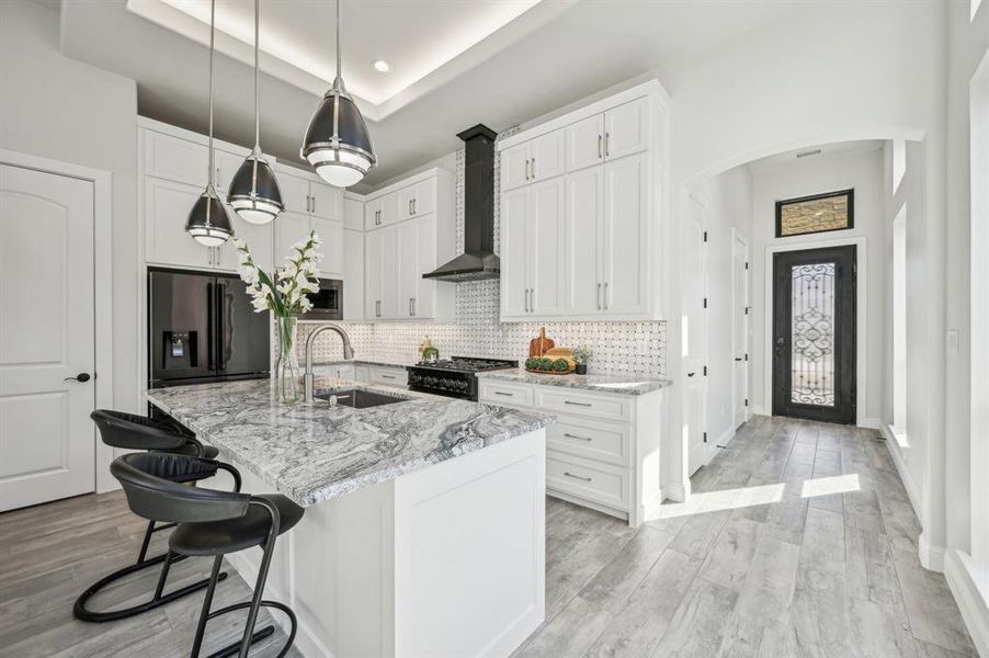 Luxury eat-in kitchen with high end Z-line appliances in black stainless steel under 12' ceilings in open concept communal space.