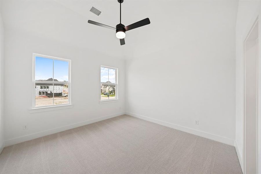 Spare room featuring light colored carpet, ceiling fan, and a high ceiling Spare room featuring light colored carpet, ceiling fan, and a high ceiling
