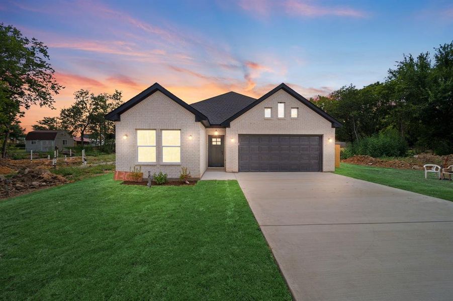 View of front of property with a garage and a yard