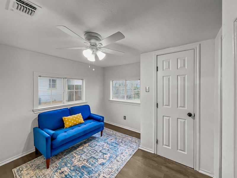 Living area featuring ceiling fan and dark wood-style flooring - great for an office or gameroom