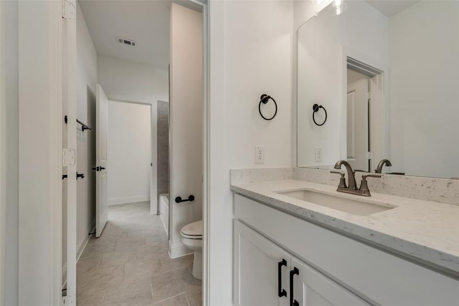 Bathroom with tile flooring, oversized vanity, and toilet