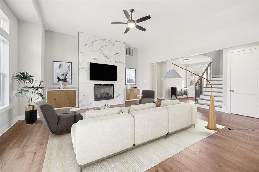 Living area with stairway, a high end fireplace, light wood finished floors, and healthy amount of natural light