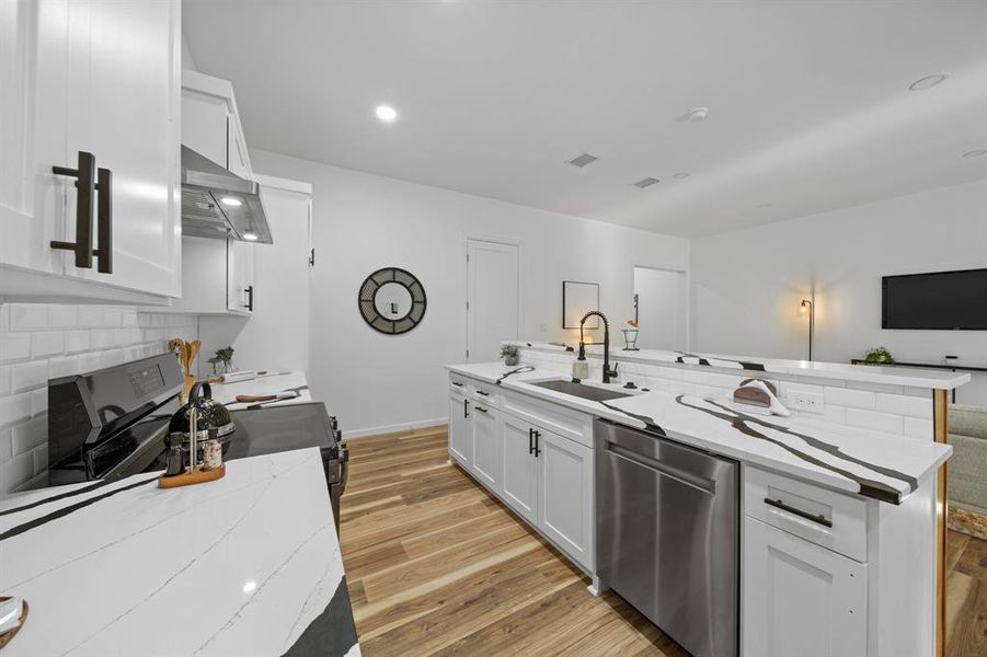 Kitchen featuring decorative backsplash, wall chimney range hood, a kitchen island, and sink