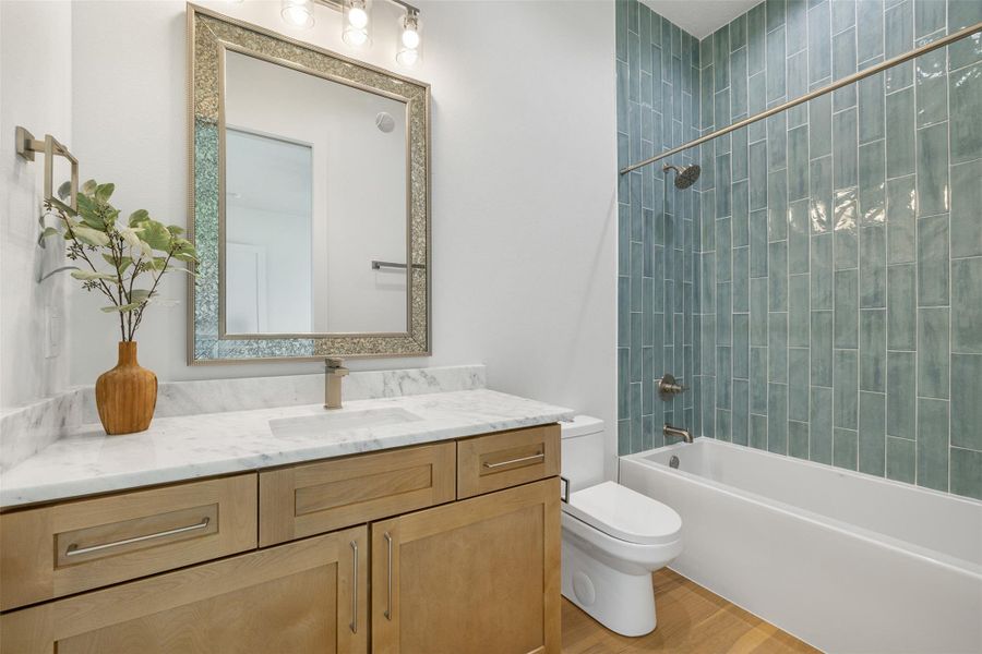 Full bath with shower / bath combination, vanity, and light wood-type flooring