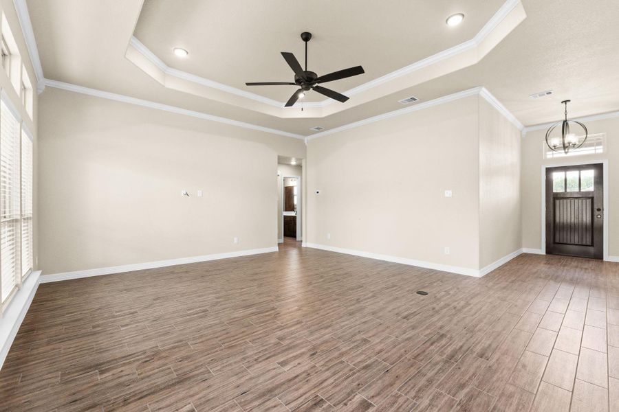 Unfurnished living room, a raised ceiling, crown molding, recessed lighting, and a ceiling fan Unfurnished living room, a raised ceiling, crown molding, recessed lighting, and a ceiling fan