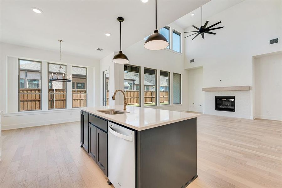 Kitchen featuring pendant lighting, white dishwasher, recessed lighting, light wood-style floors, and a center island with sink