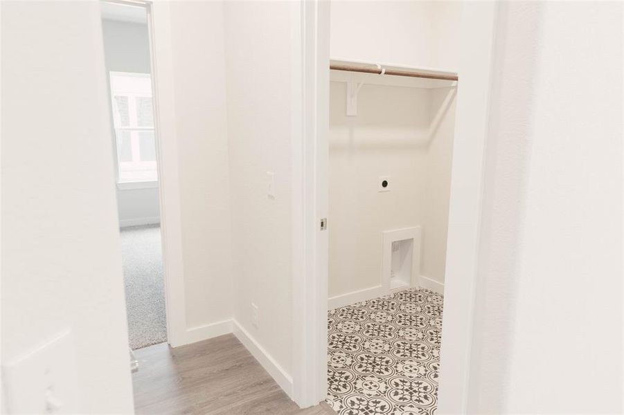 Clothes washing area featuring light colored carpet and hookup for an electric dryer