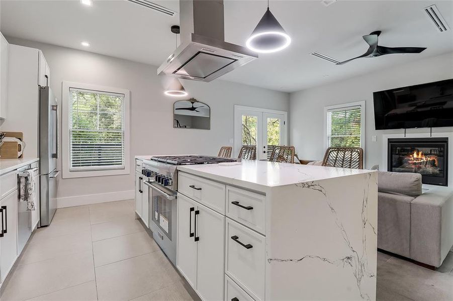 A contemporary kitchen and living area featuring a large island, sleek appliances, and a cozy fireplace.