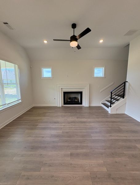 Spacious interior featuring wood-finish flooring, a contemporary ceiling fan, and recessed lighting Spacious interior featuring wood-finish flooring, a contemporary ceiling fan, and recessed lighting