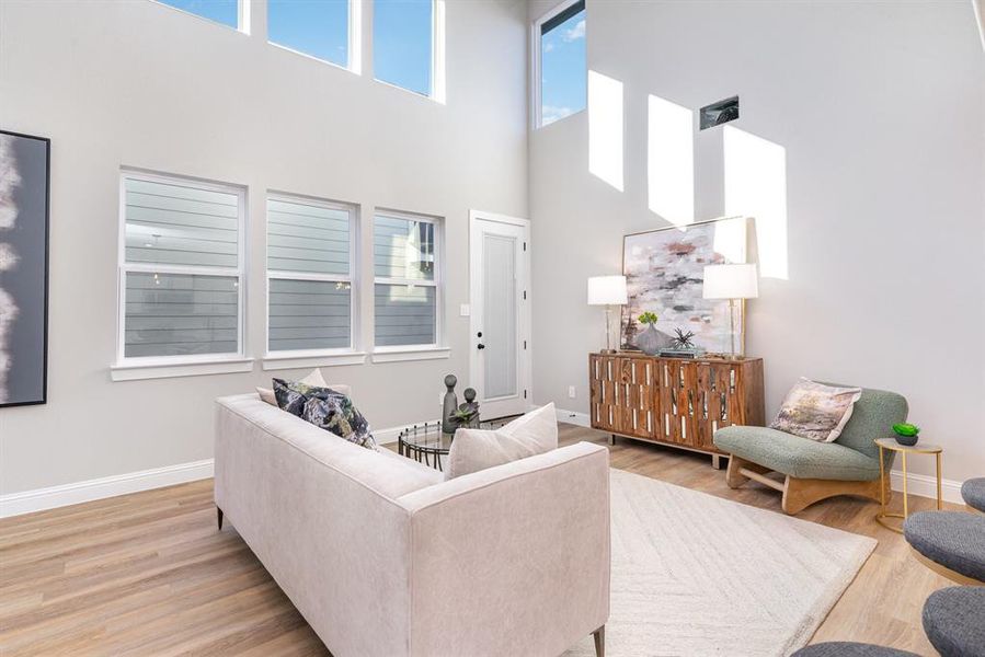 Living room with a high ceiling and light hardwood / wood-style flooring