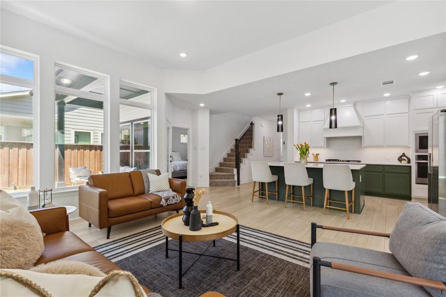 Living area with stairway, light wood-style floors, visible vents, and recessed lighting Living area with stairway, light wood-style floors, visible vents, and recessed lighting