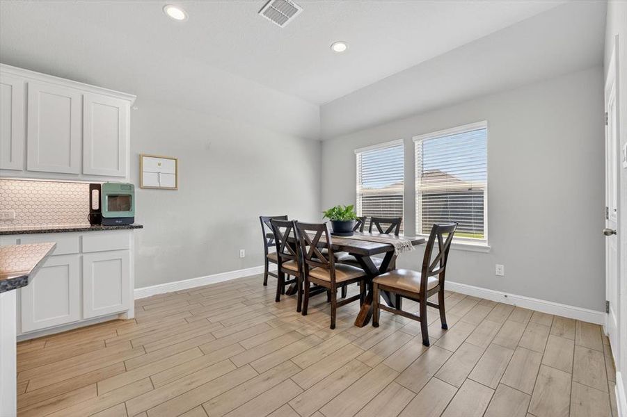 Bright dining area featuring wood-finish flooring, recessed lighting, and two large windows