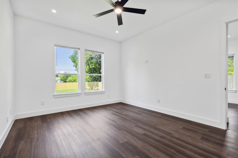 Unfurnished room featuring ceiling fan, dark wood-type flooring, and a wealth of natural light