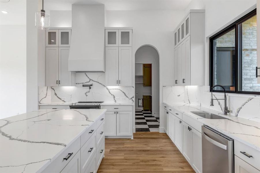 Kitchen featuring light stone counters, dishwasher, custom exhaust hood, white cabinetry, and recessed lighting