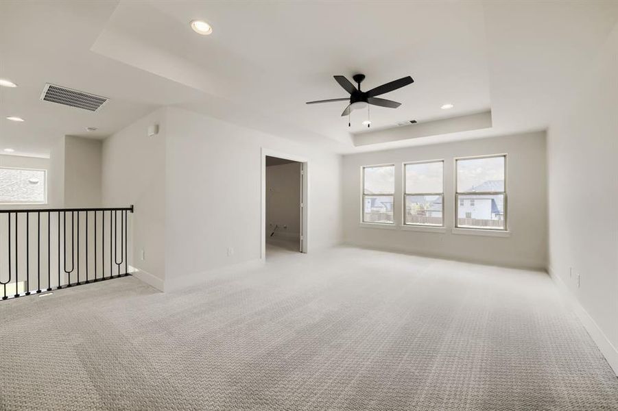 Spacious secondary living area featuring a tray ceiling with recessed lighting and a ceiling fan Spacious secondary living area featuring a tray ceiling with recessed lighting and a ceiling fan
