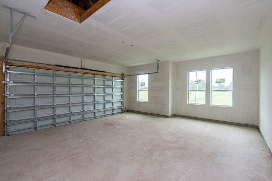 Spacious garage with a large door, high ceiling, and three windows providing ample natural light. Spacious garage with a large door, high ceiling, and three windows providing ample natural light.
