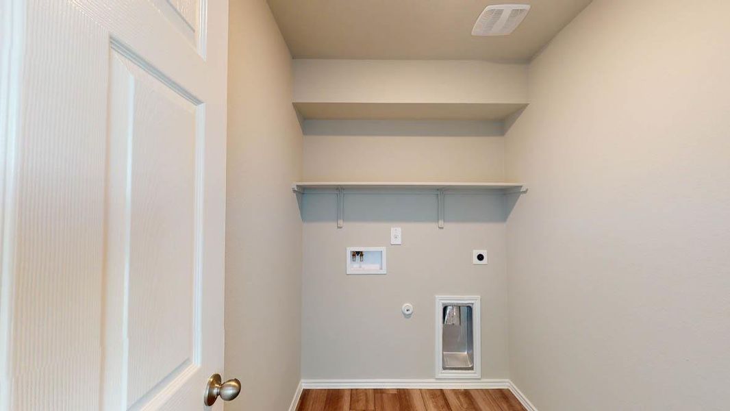 A dedicated utility space with shelving and connections for laundry appliances, offering practical storage solutions.