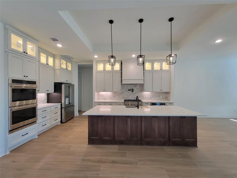 This modern kitchen features a large central island with a sleek quartz countertop, elegant pendant lighting, and ample cabinetry. It includes built-in stainless steel CAFE appliances and a spacious layout, perfect for cooking and entertaining. This modern kitchen features a large central island with a sleek quartz countertop, elegant pendant lighting, and ample cabinetry. It includes built-in stainless steel CAFE appliances and a spacious layout, perfect for cooking and entertaining.