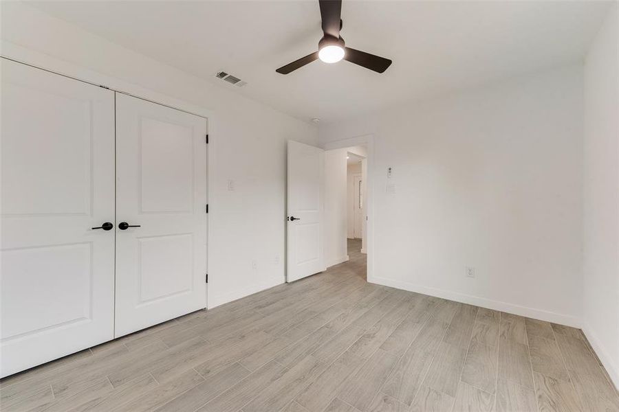 Unfurnished bedroom featuring light hardwood / wood-style flooring, a closet, and ceiling fan