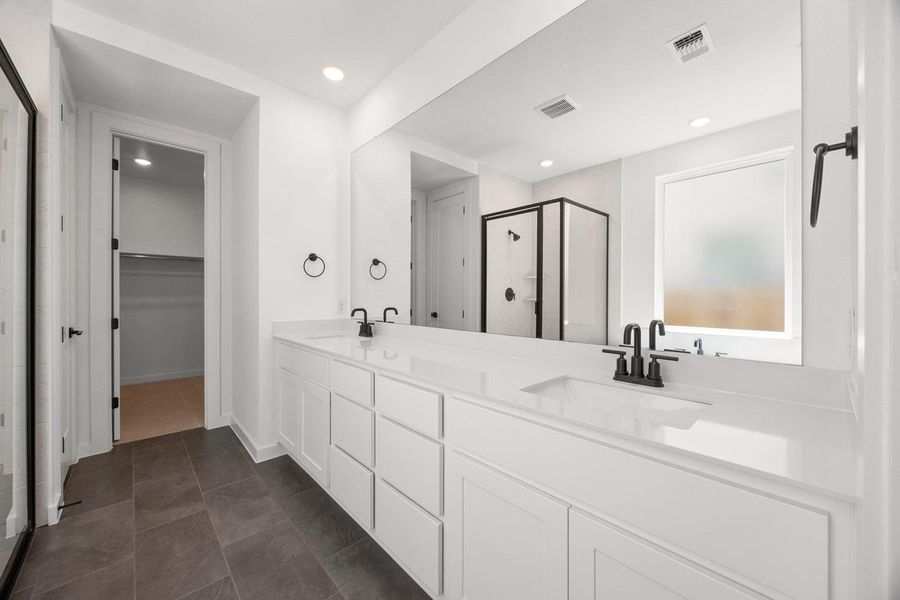 Full bath with a stall shower, double vanity, a spacious closet, dark tile patterned flooring, and recessed lighting Full bath with a stall shower, double vanity, a spacious closet, dark tile patterned flooring, and recessed lighting