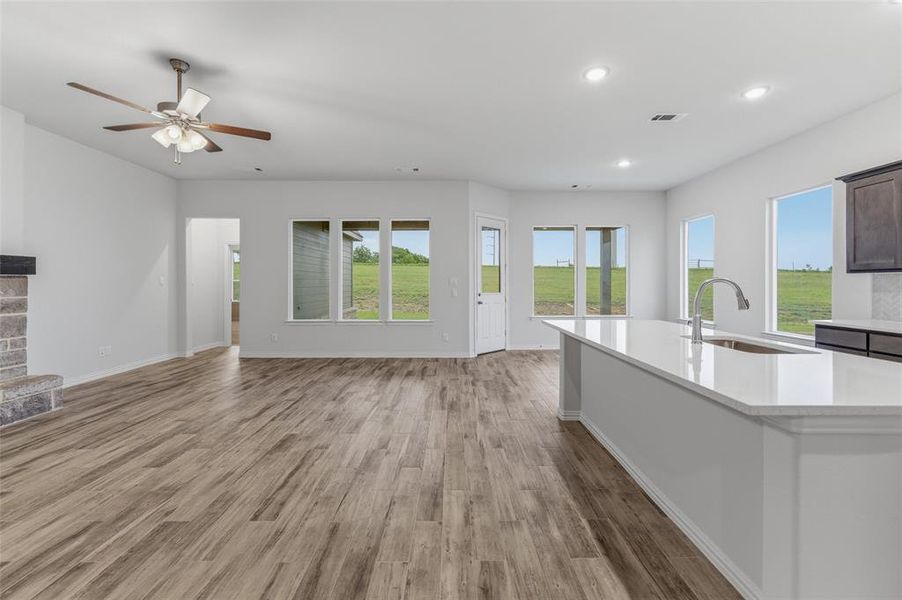 Expansive open-concept living area featuring wood-finish flooring, a ceiling fan, and recessed lighting