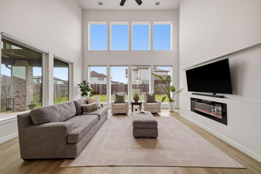A dramatic 20-foot ceiling elevates the family room, where rich luxury vinyl floors and a soaring wall of windows create an impressive sense of scale and sophistication. Expansive backyard views and abundant natural light enhance the space, while streamlined roller shades provide refined privacy and effortless light control.