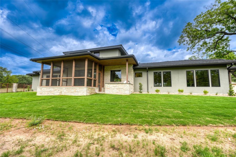 Back of property with stone siding, stucco siding, and a sunroom