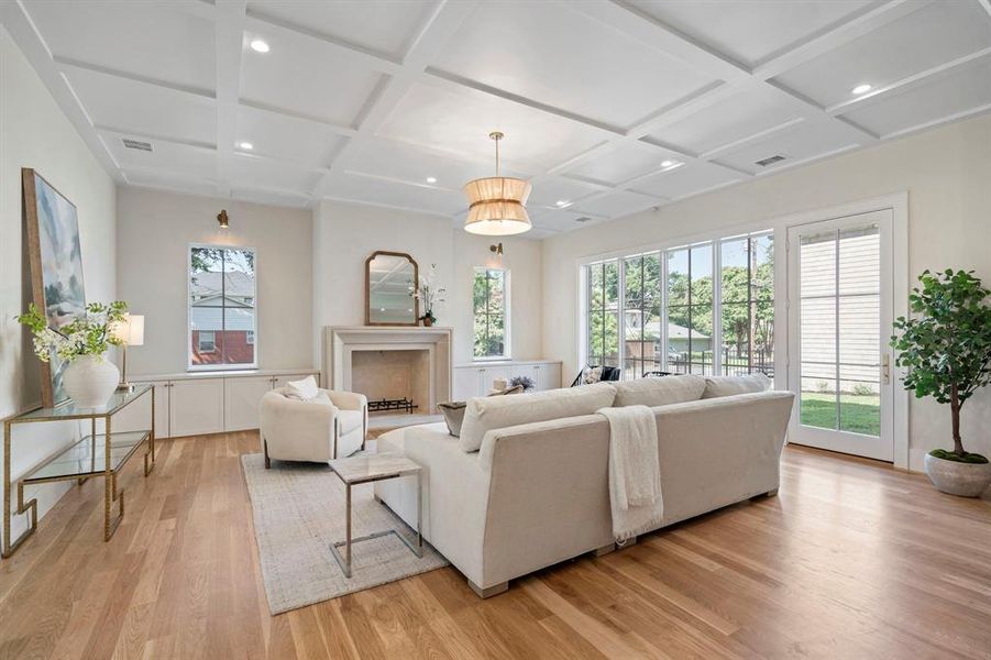 Living room with a premium fireplace, light hardwood / wood-style flooring, coffered ceiling, and a wealth of natural light