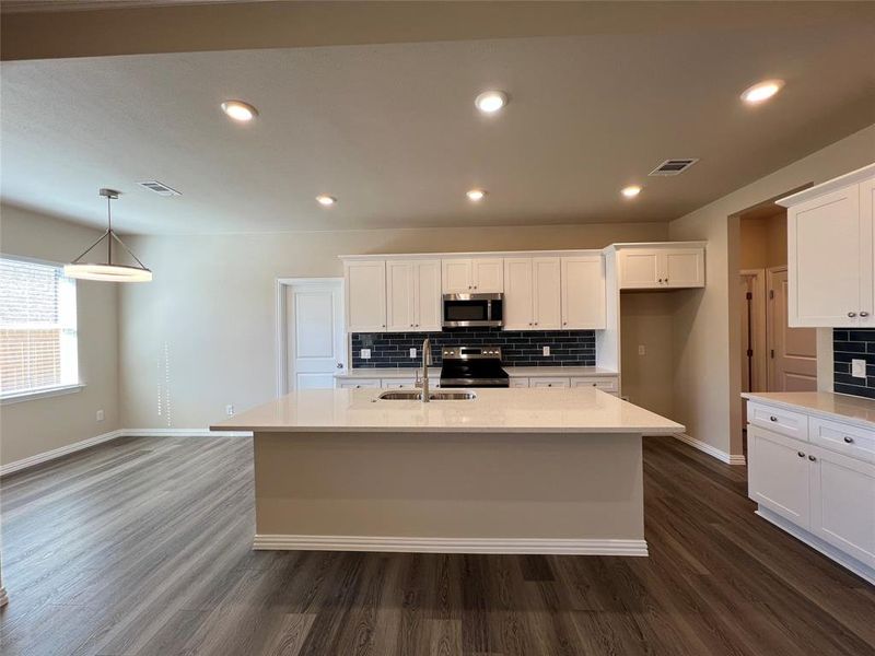 Kitchen featuring sink, stainless steel appliances, a kitchen island with sink, and dark wood-type flooring