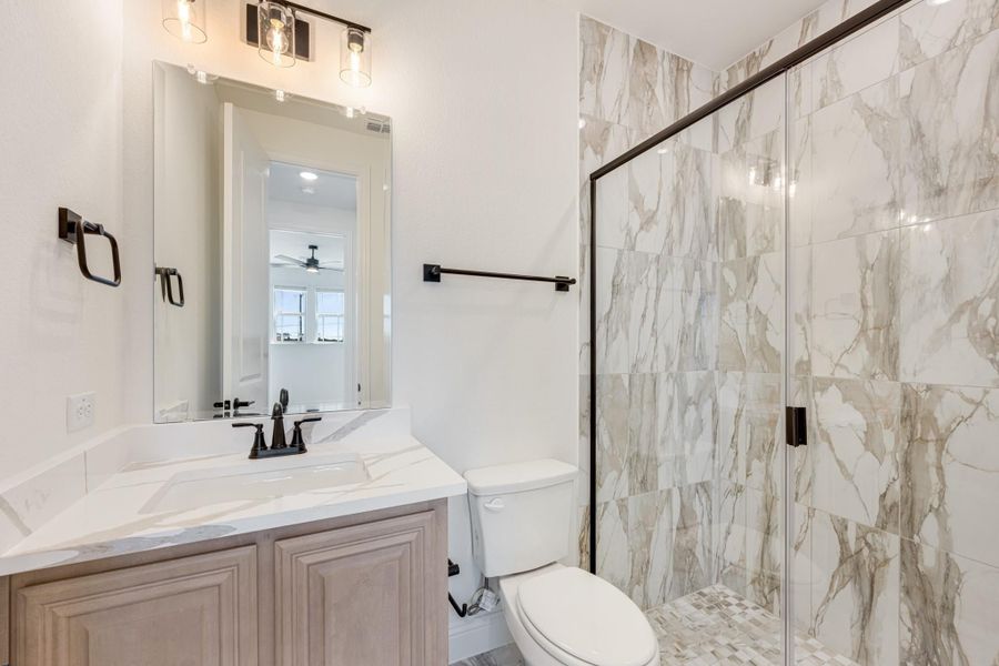 Bathroom with marble-tile walk-in shower, wood vanity, white countertop, and black fixtures Bathroom with marble-tile walk-in shower, wood vanity, white countertop, and black fixtures