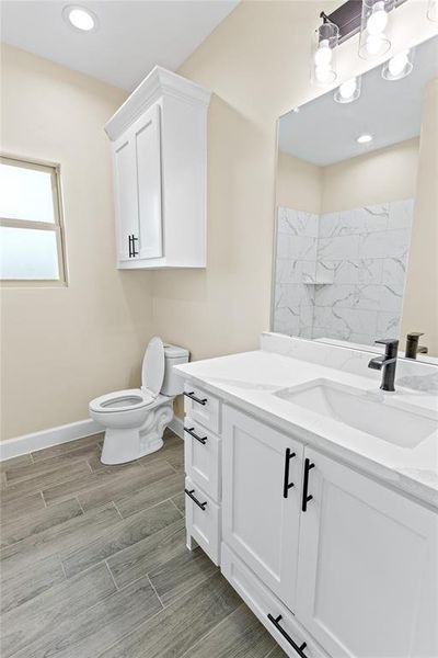 Bathroom featuring vanity, toilet, and a tile shower