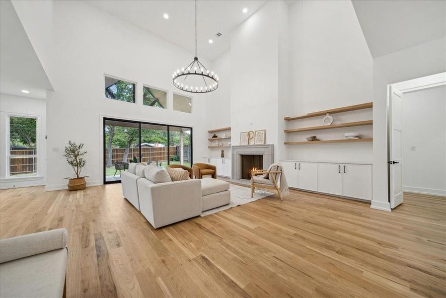 Living room featuring a high ceiling, hardwood flooring, and a notable chandelier