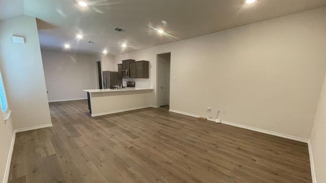 Open-concept living space featuring wood-finish flooring, recessed lighting, and a neutral color palette Open-concept living space featuring wood-finish flooring, recessed lighting, and a neutral color palette