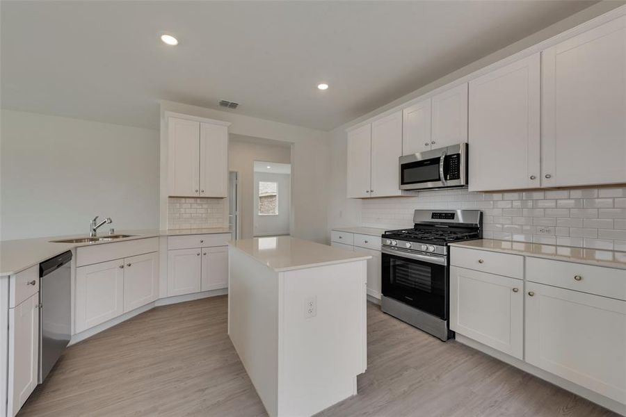 Kitchen with light hardwood / wood-style flooring, appliances with stainless steel finishes, sink, and white cabinetry