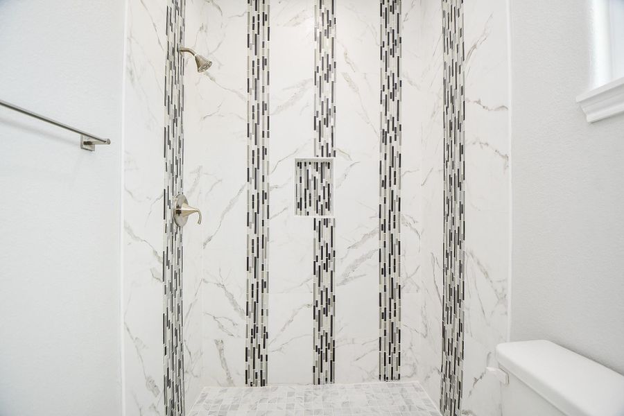 Experience luxury with a spacious master shower adorned with elegant custom tile accents.