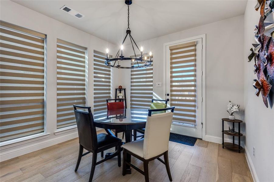 Dining space with light wood-type flooring and suspended lighting