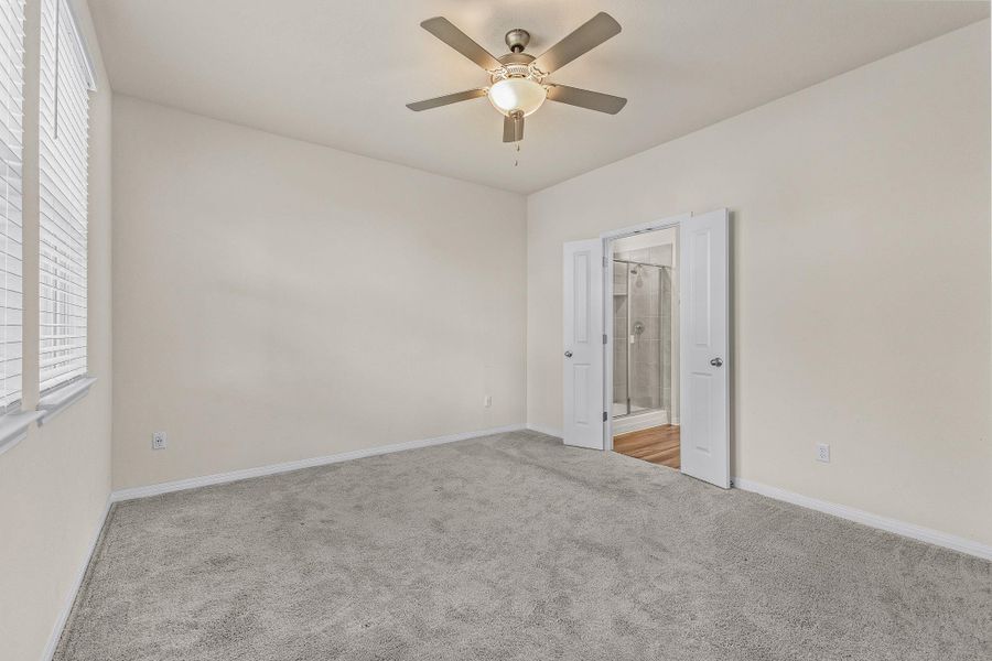 Carpeted empty room with baseboards and a ceiling fan Carpeted empty room with baseboards and a ceiling fan