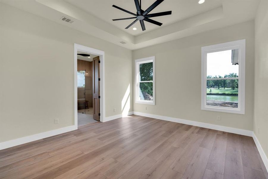 Unfurnished room with ceiling fan, a raised ceiling, and light hardwood / wood-style floors