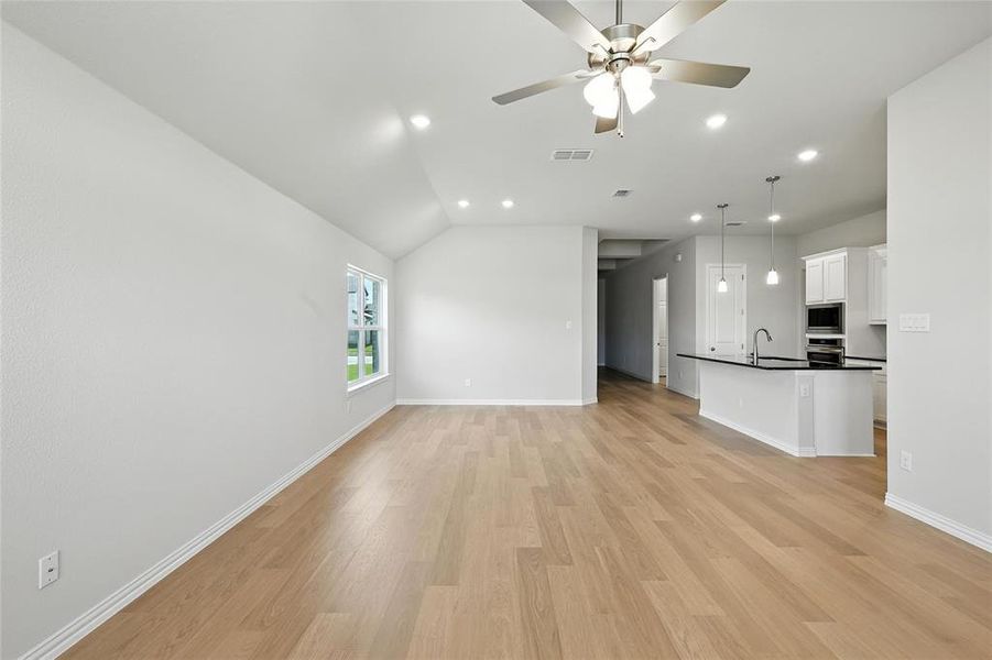 Unfurnished living room with ceiling fan, light wood-type flooring, recessed lighting, and lofted ceiling Unfurnished living room with ceiling fan, light wood-type flooring, recessed lighting, and lofted ceiling