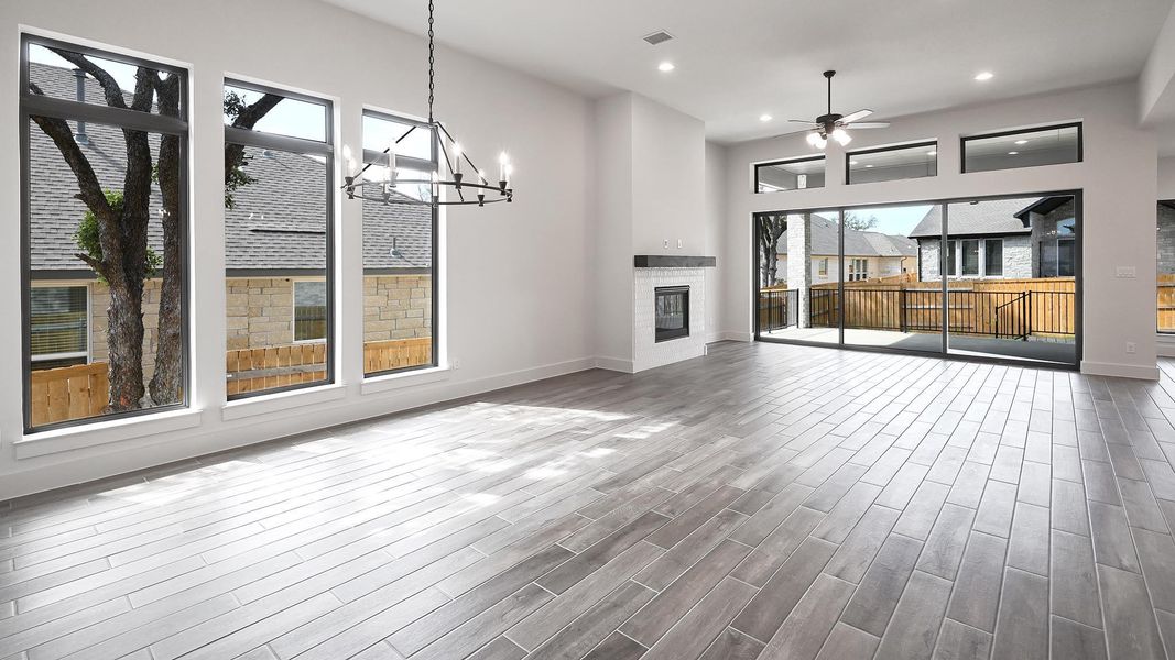 Unfurnished living room featuring a chandelier, a glass covered fireplace, recessed lighting, wood finished floors, and ceiling fan
