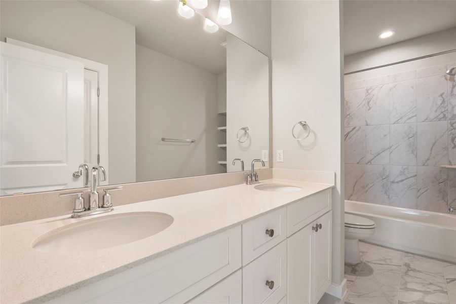 Bathroom featuring light marble finish floors, double vanity, and shower / bath combination Bathroom featuring light marble finish floors, double vanity, and shower / bath combination