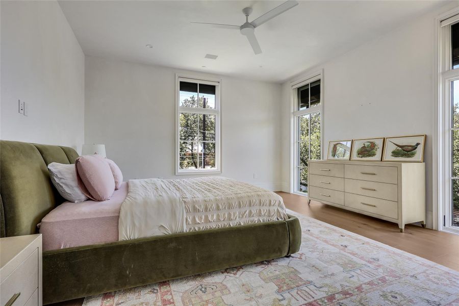 Well-lit sleeping quarters with rich wood flooring and a modern ceiling fan.