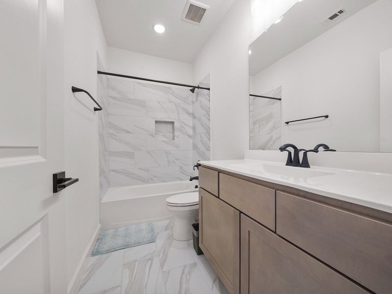The upstairs bath features modern finishes and a clean, timeless design, easily accessible from the secondary bedrooms.